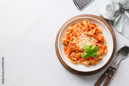 Pasta fettuccine with tomato sauce with parmesan and basil in rustic style on white background. View from above. Space for text. photo