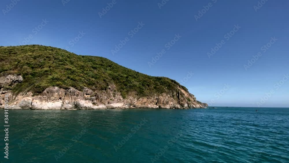View of the rocky coast of the island from the ship. Calm blue of the sea, clear blue sky with a mountain in the background View of the rocky coast of the island from the ship. Calm blue of the sea, clear blue sky with a mountain in the background