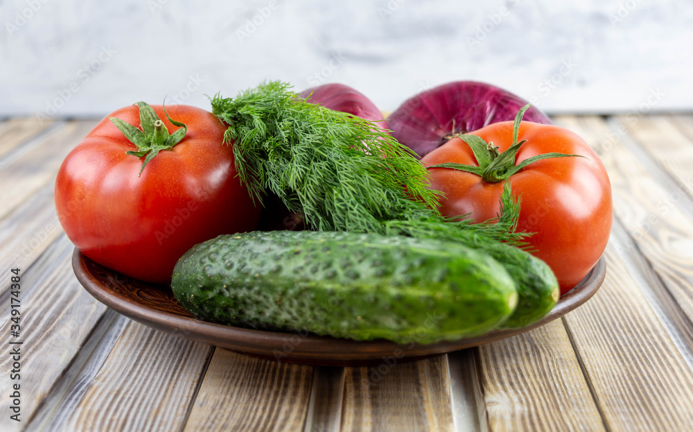 Plate with fresh vegetables close-up on a wooden background. Plate with fresh vegetables close-up on a wooden background.
