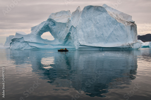 Tourists in Inflatable Rubber Boat in front of weathered iceberg, Scoresby Sund, Greenland