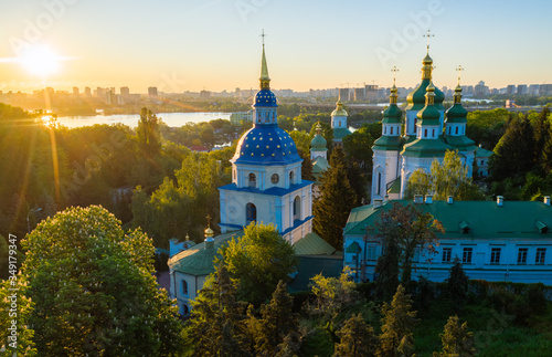 Golden and green domes of orthodox church in the middle of autumn park. Famous building is blurred.