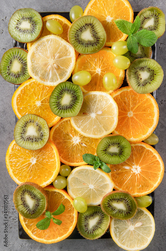 orange slices, lemon, mint, sprig , green grapes, kiwi, on a grey background ,fresh citrus and fruit,