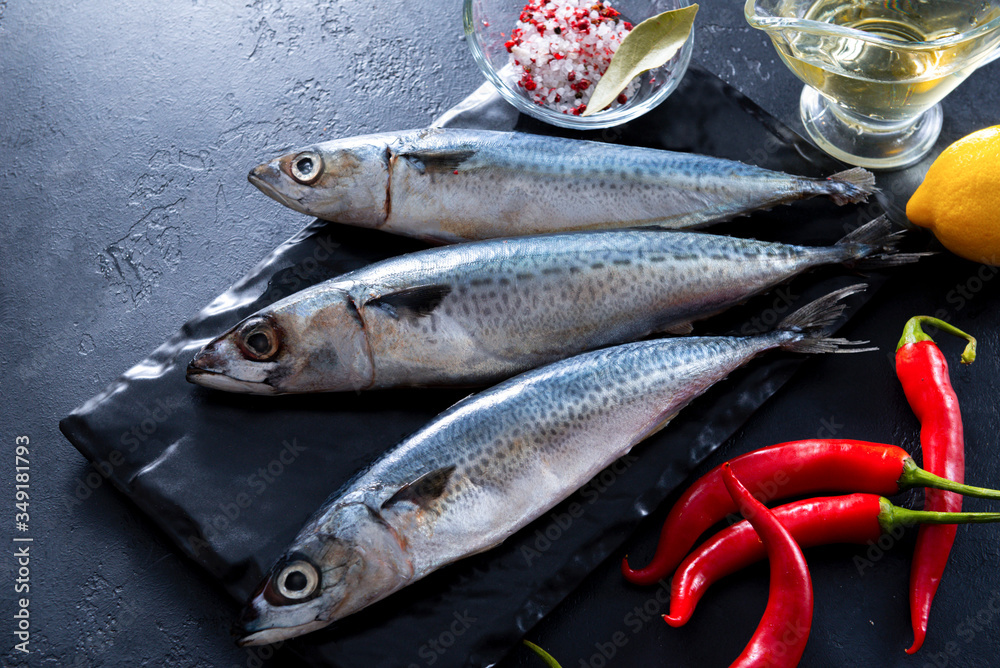 Obraz premium 3 fresh raw fish mackerel, chili pepper, lemon, oil, spices on a black background