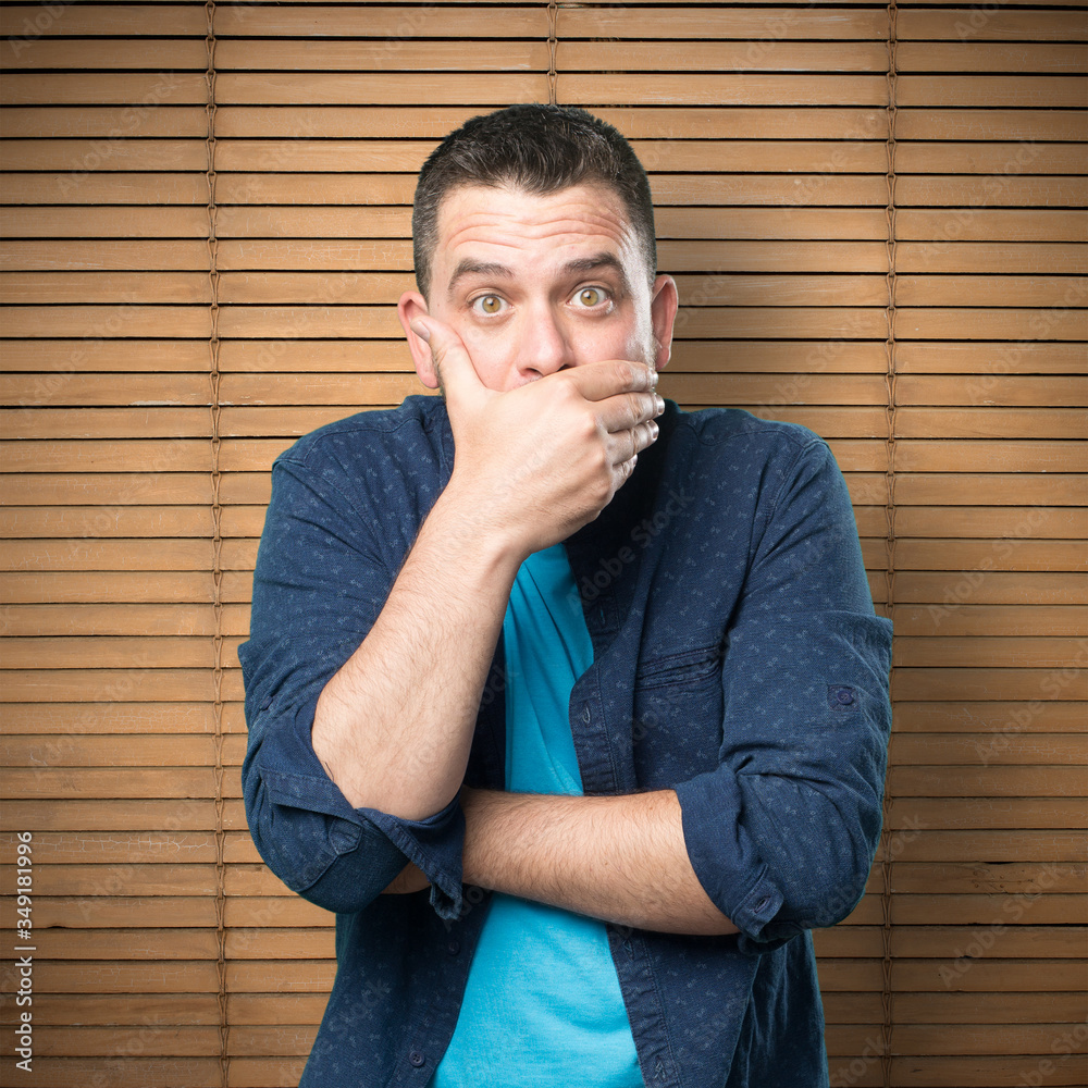 Young man wearing a blue outfit. Looking surpresided and covering his mouth with his hand. Young man wearing a blue outfit. Looking surpresided and covering his mouth with his hand.