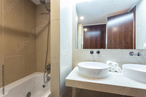 Modern bathroom with bathtub  mirror and washbasin. European hotel design.