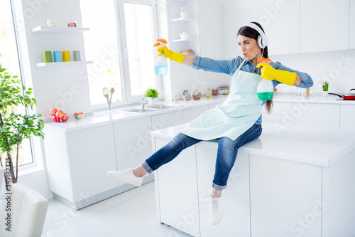 Portrait of her she nice attractive cheerful cheery funny funky playful housewife using spray having fun fighting killing dust struggling in modern light white interior kitchen house