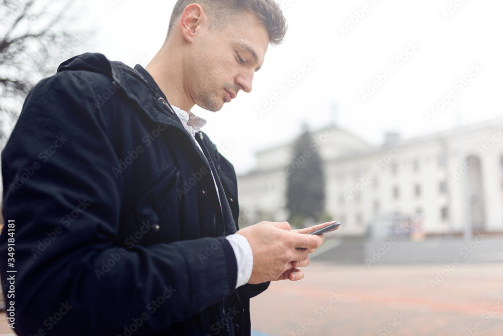 Young man typing on phone on the street