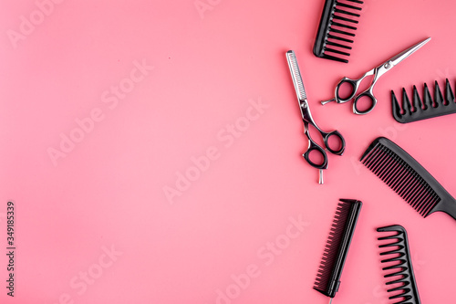 Combs, hairbrush, scissors - hairdresser eqiupment - on pink table top-down space for text