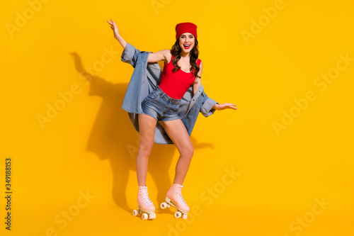 Full length photo of positive cheerful teenager youngster girl enjoy sporty rest relax weekend ride roller quads wear red headwear tank-top denim isolated over bright color background