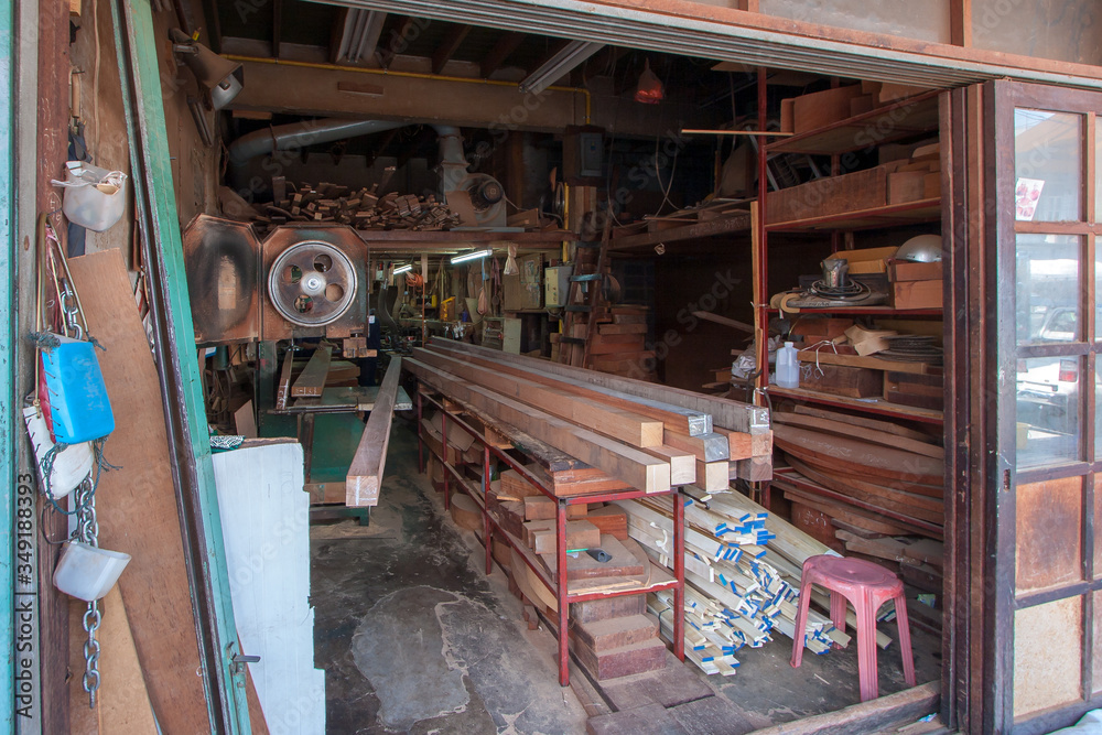 Street wood workshop in Thailand. Circular machine. A lot of long bars and blanks for work. Many shelves. Horizontal.