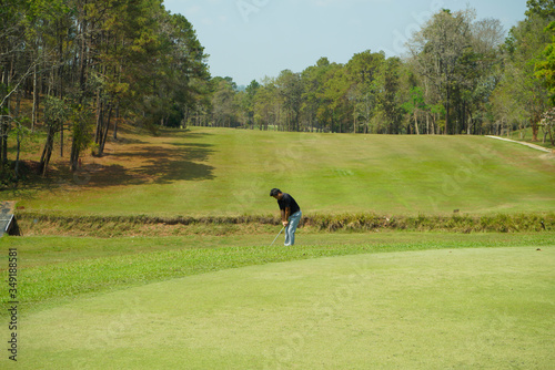 Golfer addressing the ball as he is about to tee off with a driver on a short four par. photo