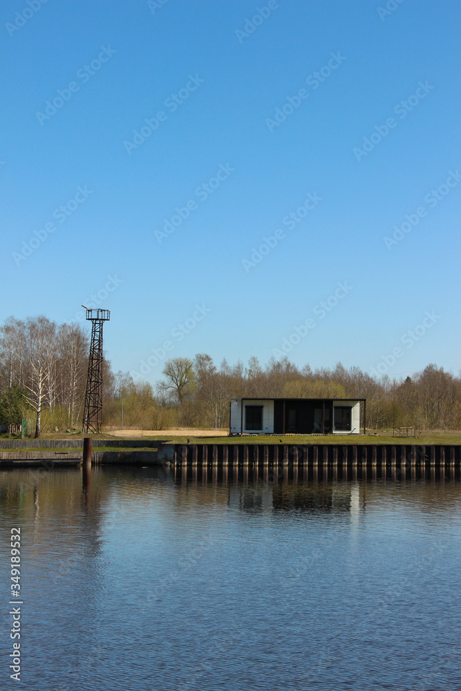 Fototapeta premium One-storey modular house that stands at the river shore. Container housing that stands aside from the living area.