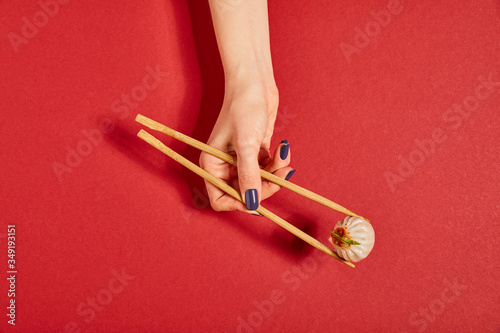 top view of woman holding chopsticks with steamed bun on red