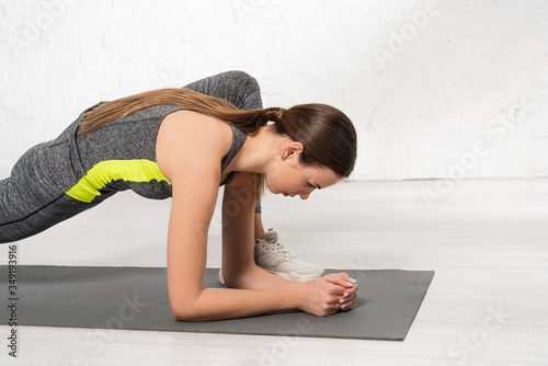 profile of sportive young woman warming up on fitness mat