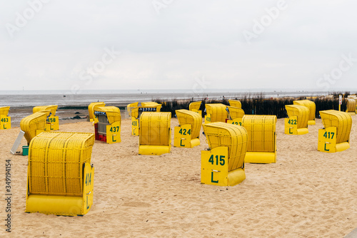 Sandy beach and typical hooded beach chairs in Cuxhaven in the North Sea coast a cloudy day of Summer. Germany 