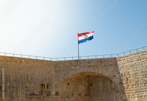 Proud and shaky Croatian flag on a blue background, on a fortress wall photo