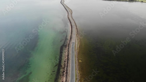 Aerial of long road in the middle of the ocean that goes to a small Danish island with cars driving on it in the summer photo