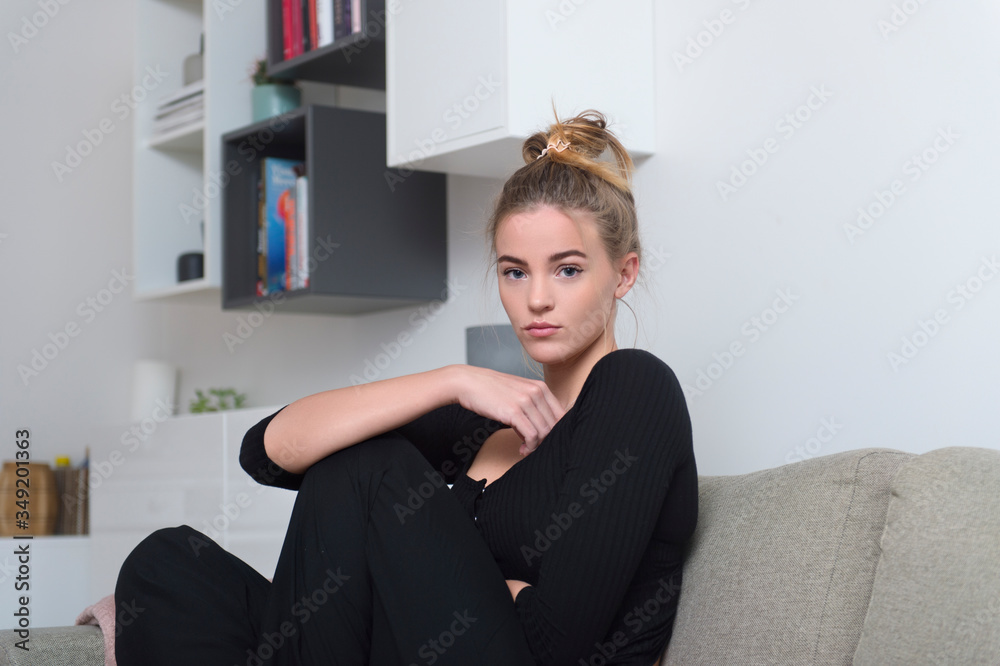 Beautiful girl sitting on sofa in living room at home Beautiful girl sitting on sofa in living room at home