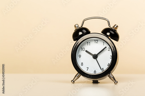 Black retro alarm clock with bells on a wooden table, daily routine concept.