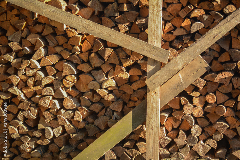 stacked firewood reinforced with boards from which the shadow shines in the sunlight stacked firewood reinforced with boards from which the shadow shines in the sunlight