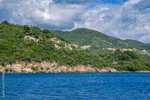Beautiful landscape with sea bay, rocks and cliffs, blue sky and mountains on the horizon. Corfu Island, Greece.  © elenakirey