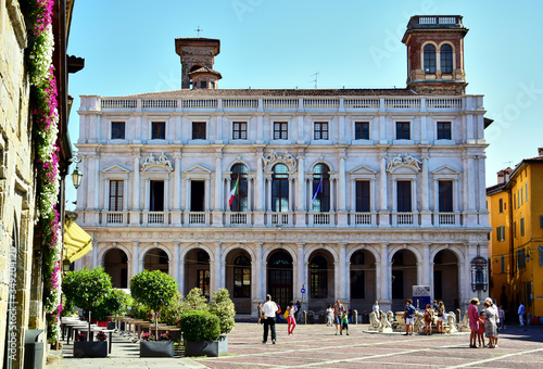Bergamo / Lombardy, Italy - Biblioteca Civica Angelo Mai, occupy the Palazzo Nuovo di Bergamo on the Piazza Vecchia, a white building, people are walking in the square in front of it.