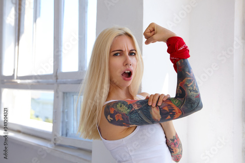 Canvas Print Expressive young attractive tattooed woman with long blonde hair frowning her fa