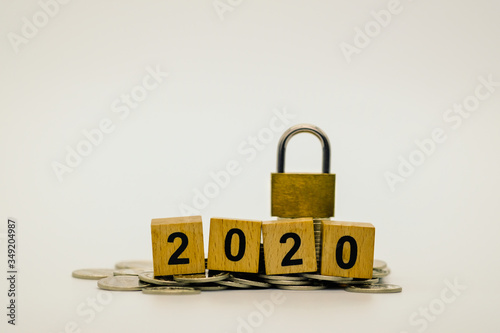 2020 New year, Business, Money, Finance and Saving concept. Closeup of wooden block number on silver coins and master key on white background with copy space text.