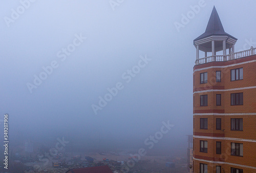 Thick fog overthe city. Absolutely nothing to be seen. In the frame of the building with the roof of Muslim style. photo