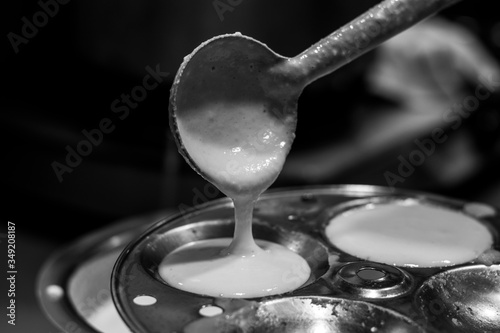 Filling  idli batter in  round shaped stencil or making idlis , south indian dish.Deep Nahar.