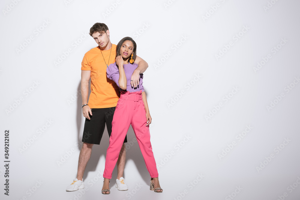 full length view of handsome guy holding hand on shoulder of trendy african american girlfriend on white background full length view of handsome guy holding hand on shoulder of trendy african american girlfriend on white background