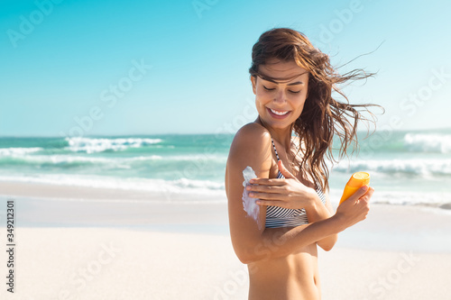 Woman in bikini applying sunscreen photo
