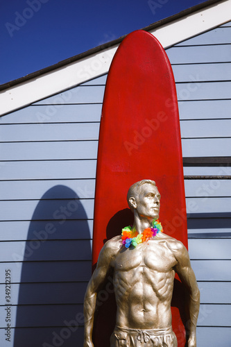 Statue of a golden waterman surfer with a red longboard surfboard photo