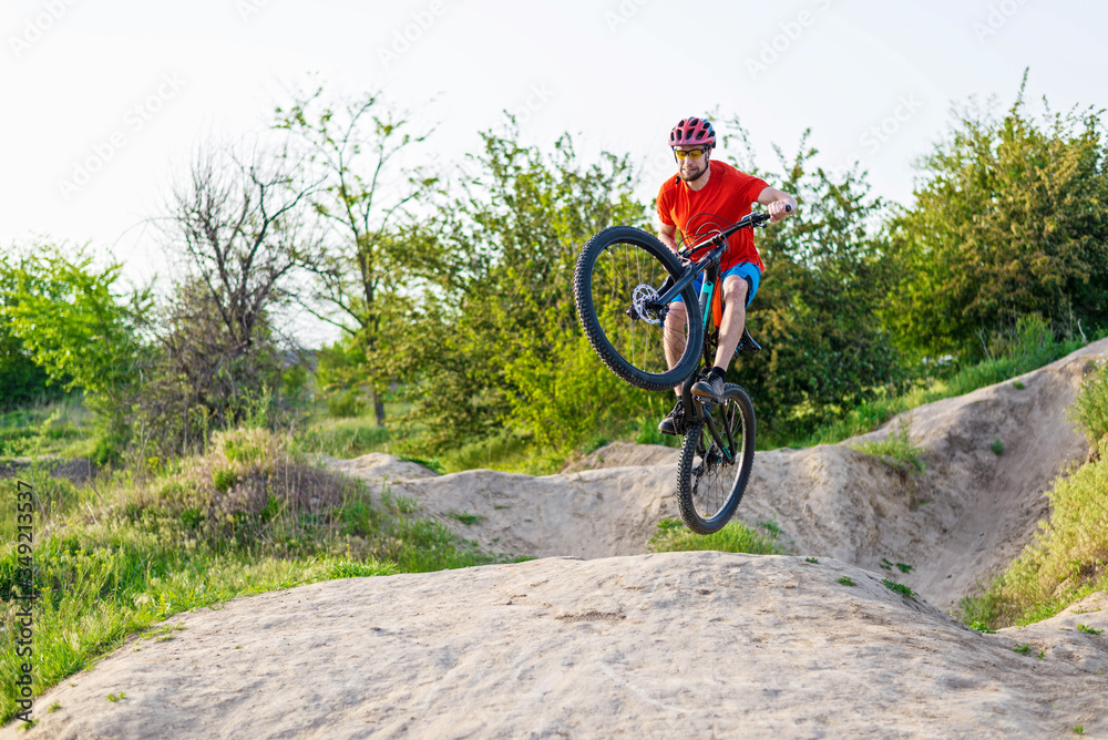 Professional cyclist in a bright T-shirt performs a jump. Professional cyclist in a bright T-shirt performs a jump.