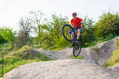 Professional cyclist in a bright T-shirt performs a jump.