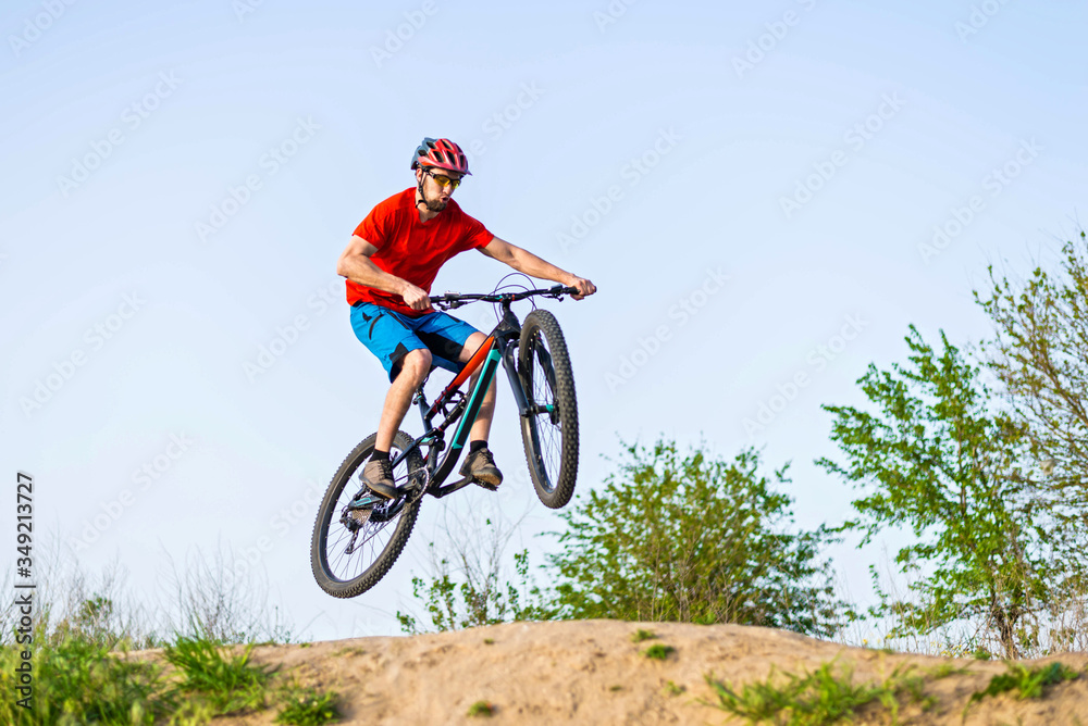 Professional cyclist in a bright T-shirt performs a jump.