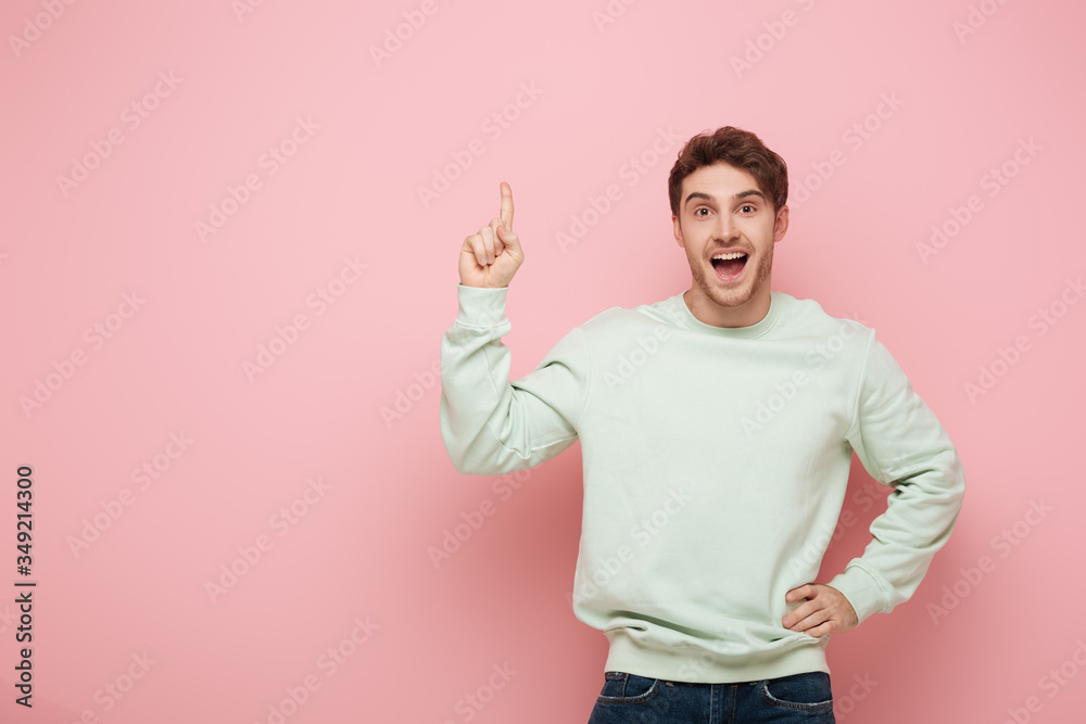 excited guy showing idea sign while standing with hand on hip and looking at camera on pink background excited guy showing idea sign while standing with hand on hip and looking at camera on pink background