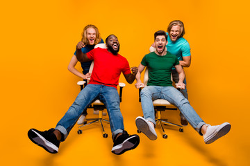 Full length photo two blonde hair men have office chair ride challenge afro american guy enjoy fun pal shout afraid fast speed wear t-shirt denim jeans isolated bright color background