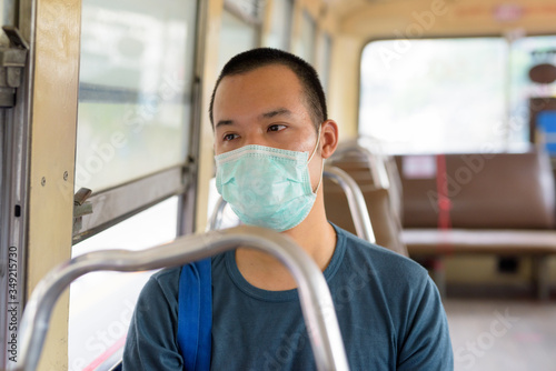 Face of young Asian man with mask riding the bus with distance