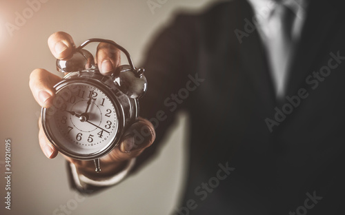 Businessman holding retro alarm clock. time management and time is money concept.