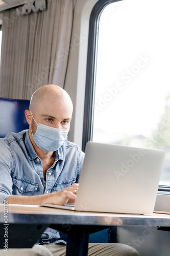 Zugfahrt mit Munschutzmaske, Mann arbeitet am Laptop