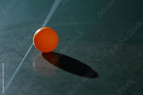 Orange ping pong ball on a green table