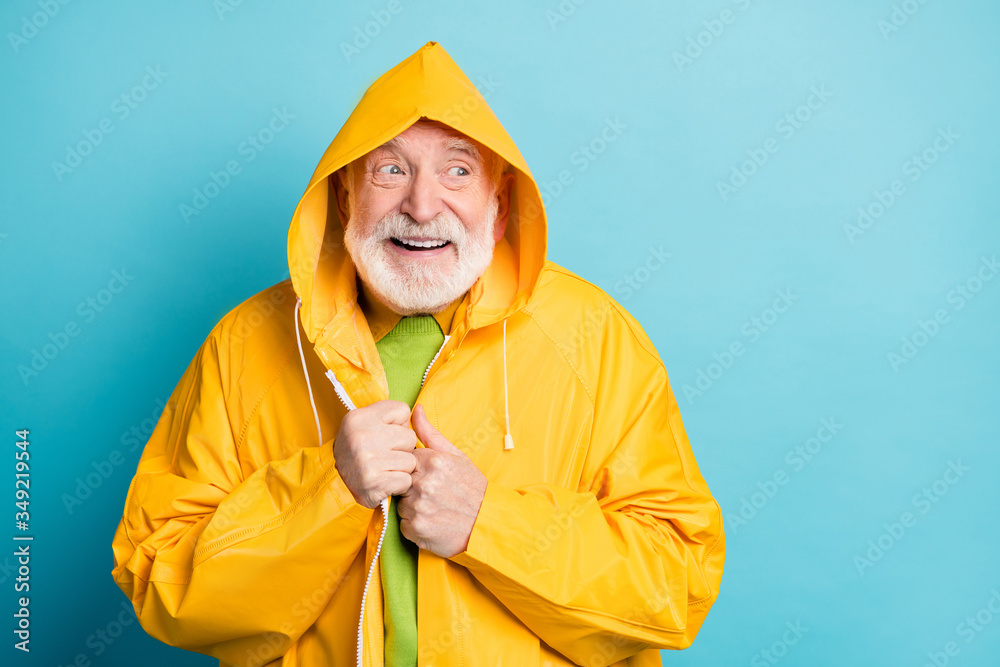Portrait of his he nice attractive cheerful cheery grey-haired man wearing new modern yellow warm overcoat windy cold weather cyclone isolated on bright vivid shine vibrant blue color background