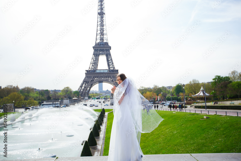 Beautiful bride in rich wedding dress whirls on the square before the Eiffel Tower