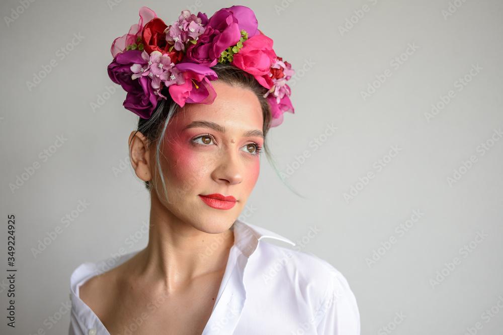 Naklejka premium Sensual woman in floral wreath. Portrait of beautiful young woman with red lips dressed in a white blouse.