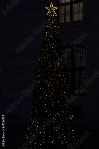 Christmas simple decorated tree, during the night, with lights and red ribbon in the middle