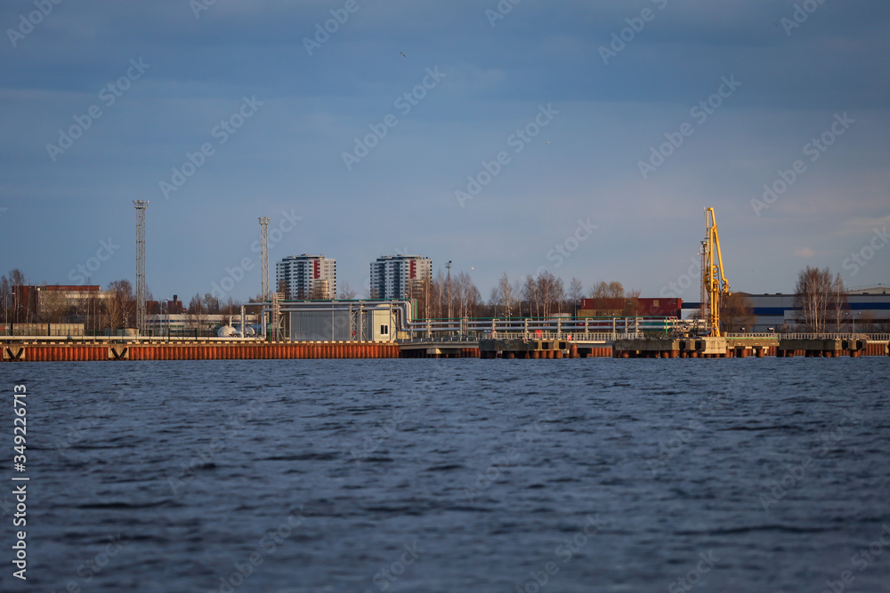 Rural dock view of river Daugava, cranes and city in the background.