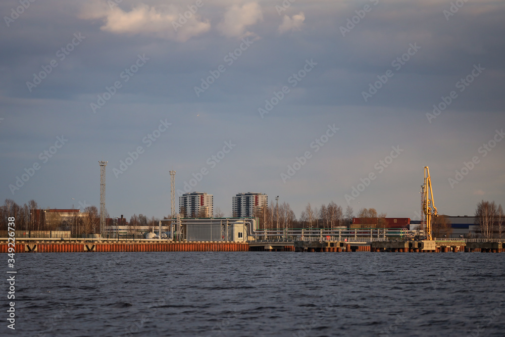 Rural dock view of river Daugava, cranes and city in the background.