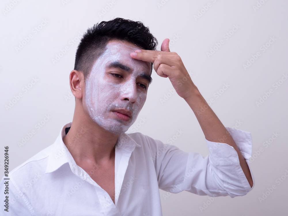 Asian handsome young man applying cream at his face with smiley face, Skin care concept Asian handsome young man applying cream at his face with smiley face, Skin care concept