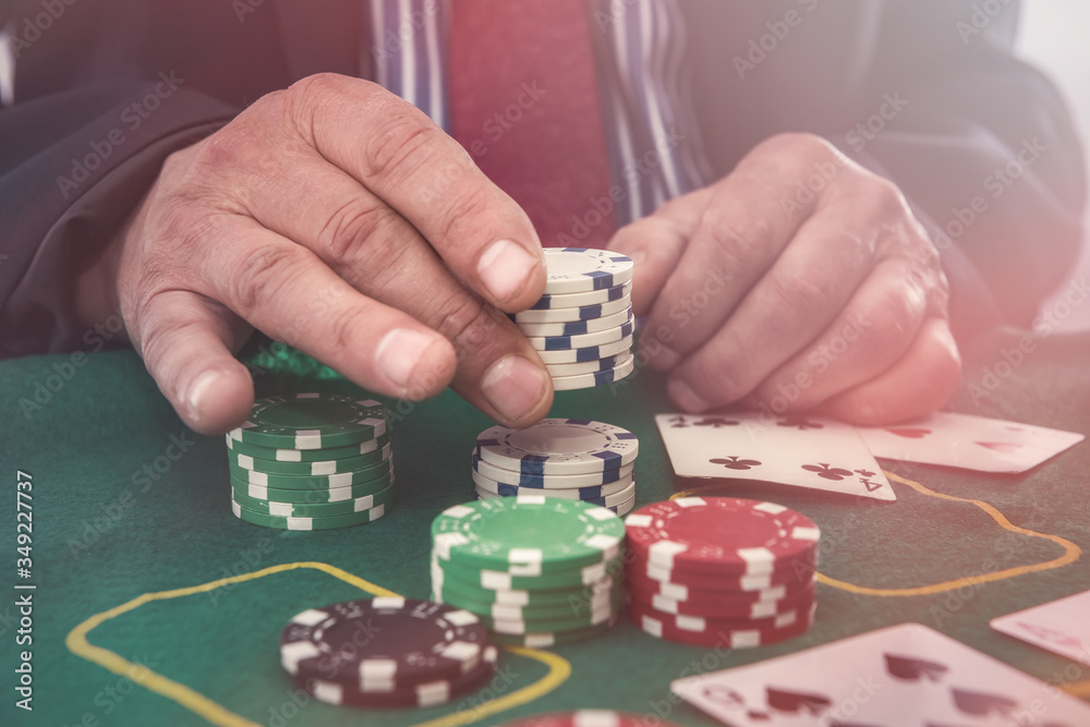 Man in casino looking at playing cards and stack of token chips Man in casino looking at playing cards and stack of token chips